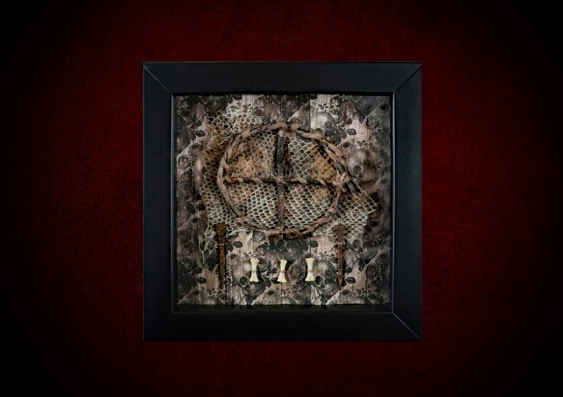 Repurposed black shadow box frame featuring a willow sun wheel, shed snake skin remnant, and bones against a sepia skulls and roses backdrop.