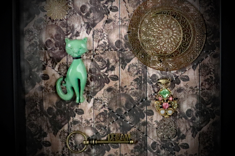 Macro view of a unique metal key reading "DREAM" at the base of an occult curiosity display frame representing the subconscious mind.