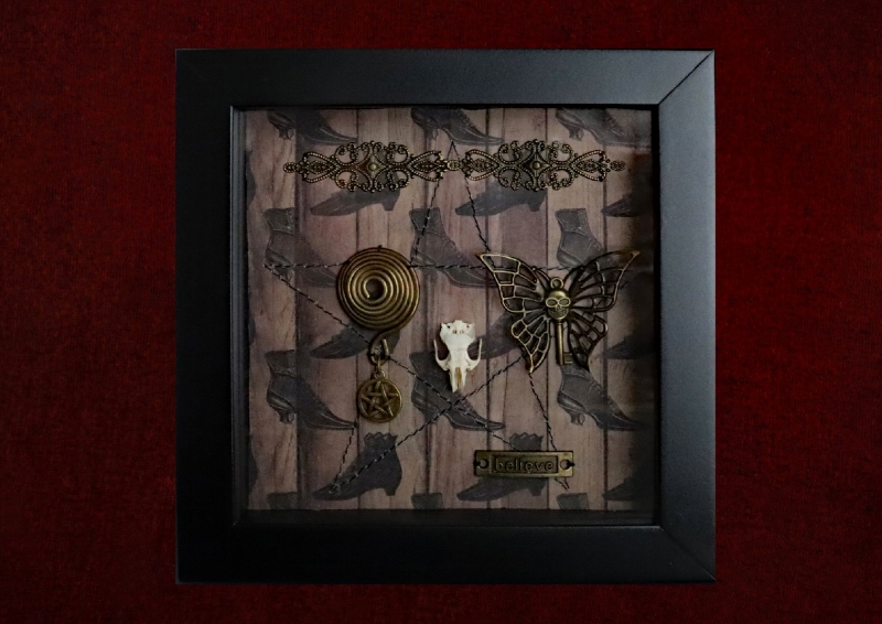 Detailed view of a delicate rat skull specimen resting on a machine-sewn pentagram inside a pagan curio display.