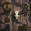 Detailed shot of a spiral pentacle charm and a golden butterfly with a skull-key body in a traditional gothic shadow box.