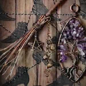Close-up view of a wire-wrapped amethyst tree of life sculpture anchoring the right side of an occult curiosity display.