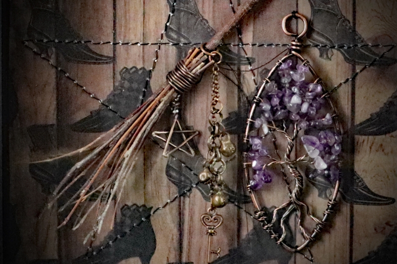 Close-up view of a wire-wrapped amethyst tree of life sculpture anchoring the right side of an occult curiosity display.