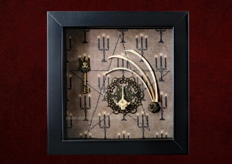 Detailed view of an ornate gold hare’s head key set on a machine-sewn pentagram on a sepia candelabra background.