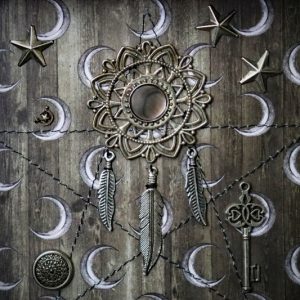 Macro photograph focusing on the fine lines of the sepia-toned backdrop, the metallic sheen of the key, and the delicate feather charms hanging from the mandala.