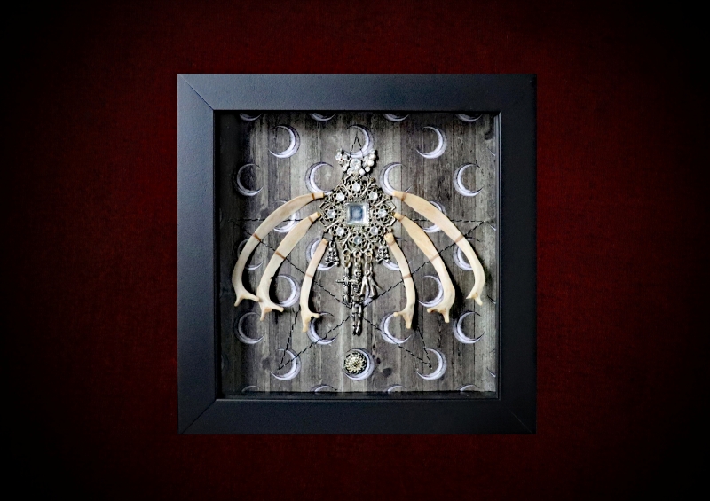 Repurposed black shadow box frame featuring a diamond-shaped vintage diamante charm with memento mori drops, flanked by six authentic hare bones on a sepia pentagram backdrop.