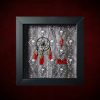 Repurposed black shadow box frame featuring an asymmetrical layout with a skull dreamcatcher, red lorikeet feathers, a red enamel coffin, and red painted lettering reading ‘FUCK’ on a skulls and ivy backdrop.