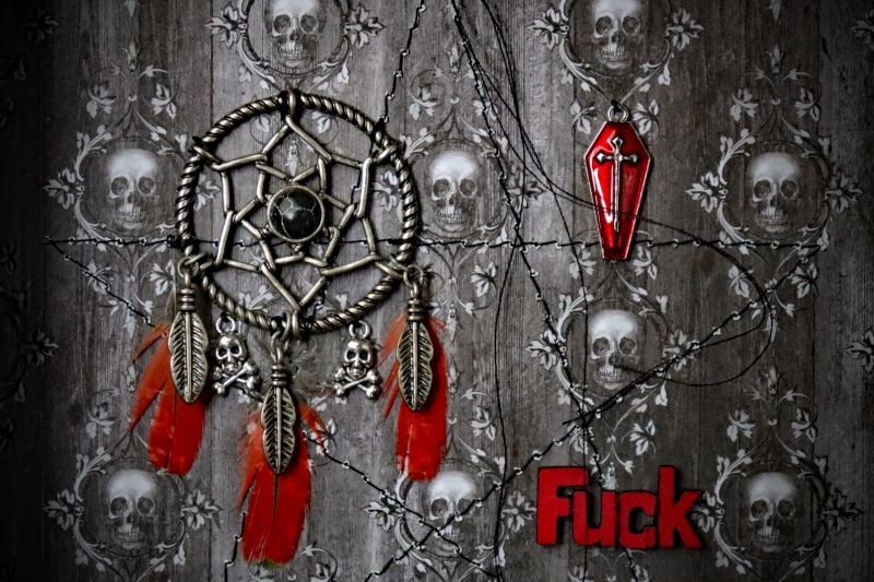 Detailed close-up focusing on the vibrant red enamel coffin charm with an inset cross and the bold red painted word ‘FUCK’ beneath it.